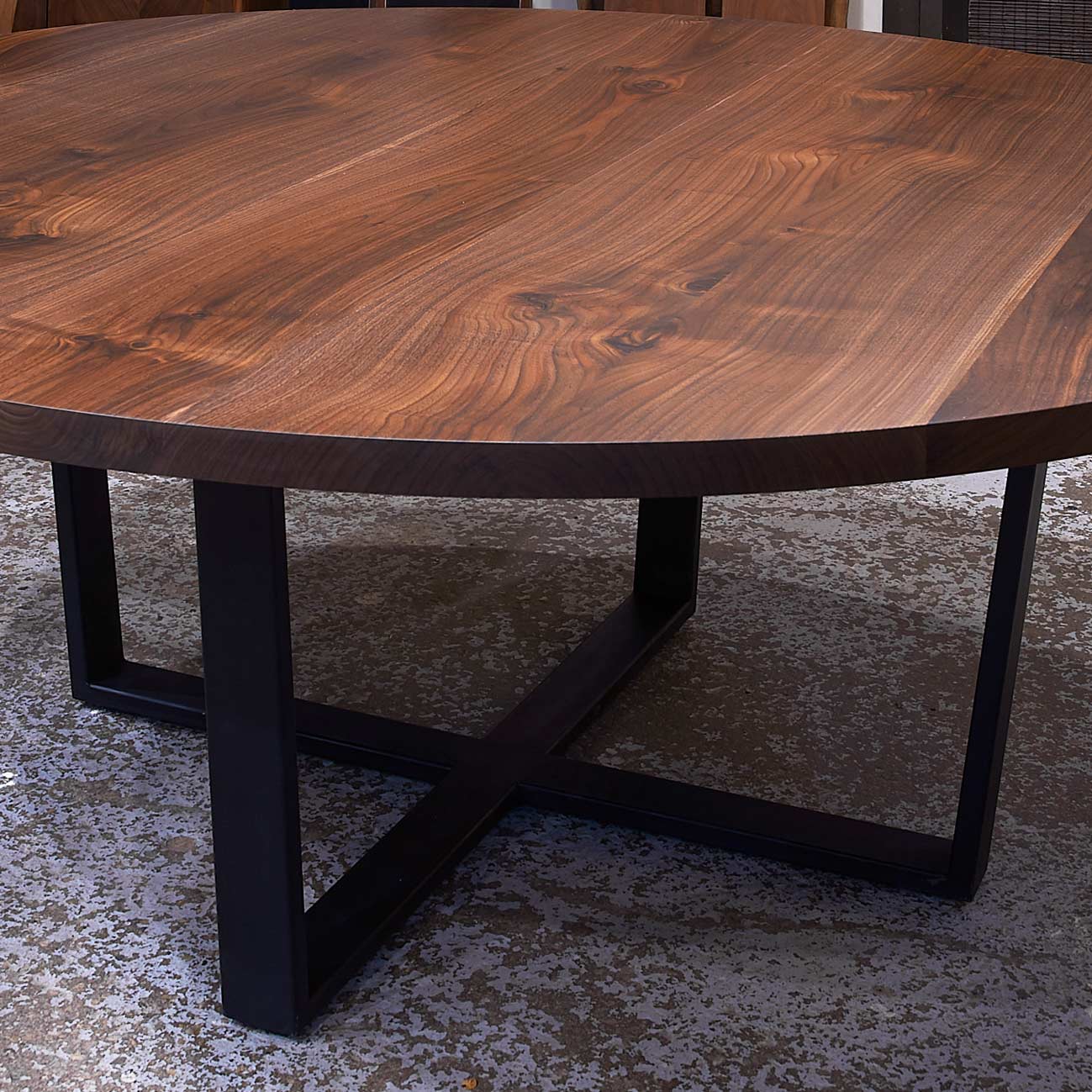 72" diameter round solid wood Walnut dining table with crossed trapezoid base at the Chicago area table showroom