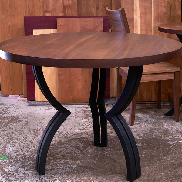 Stained Sapele Mahogany round dining table with steel arched legs in our Chaicago Area Table Showroom